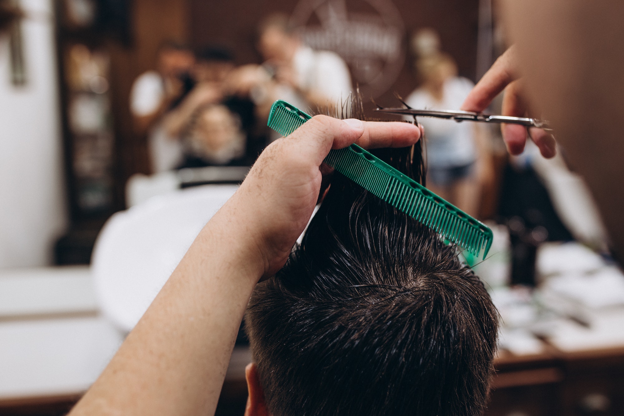 Master cuts hair and beard of men in the barbershop, hairdresser makes hairstyle for a young man